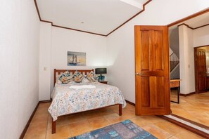 Une chambre à coucher avec un lit, une table de chevet, un tableau et une porte en bois.