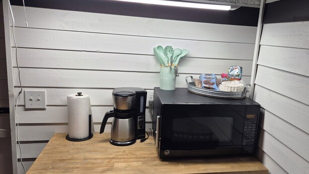Een kitchenette met een koffiezetapparaat, magnetron en een schaal met snacks.