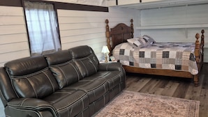 Een slaapkamer met een houten baldakijnbed, een leren bank en een kamerbreed tapijt met dessin.