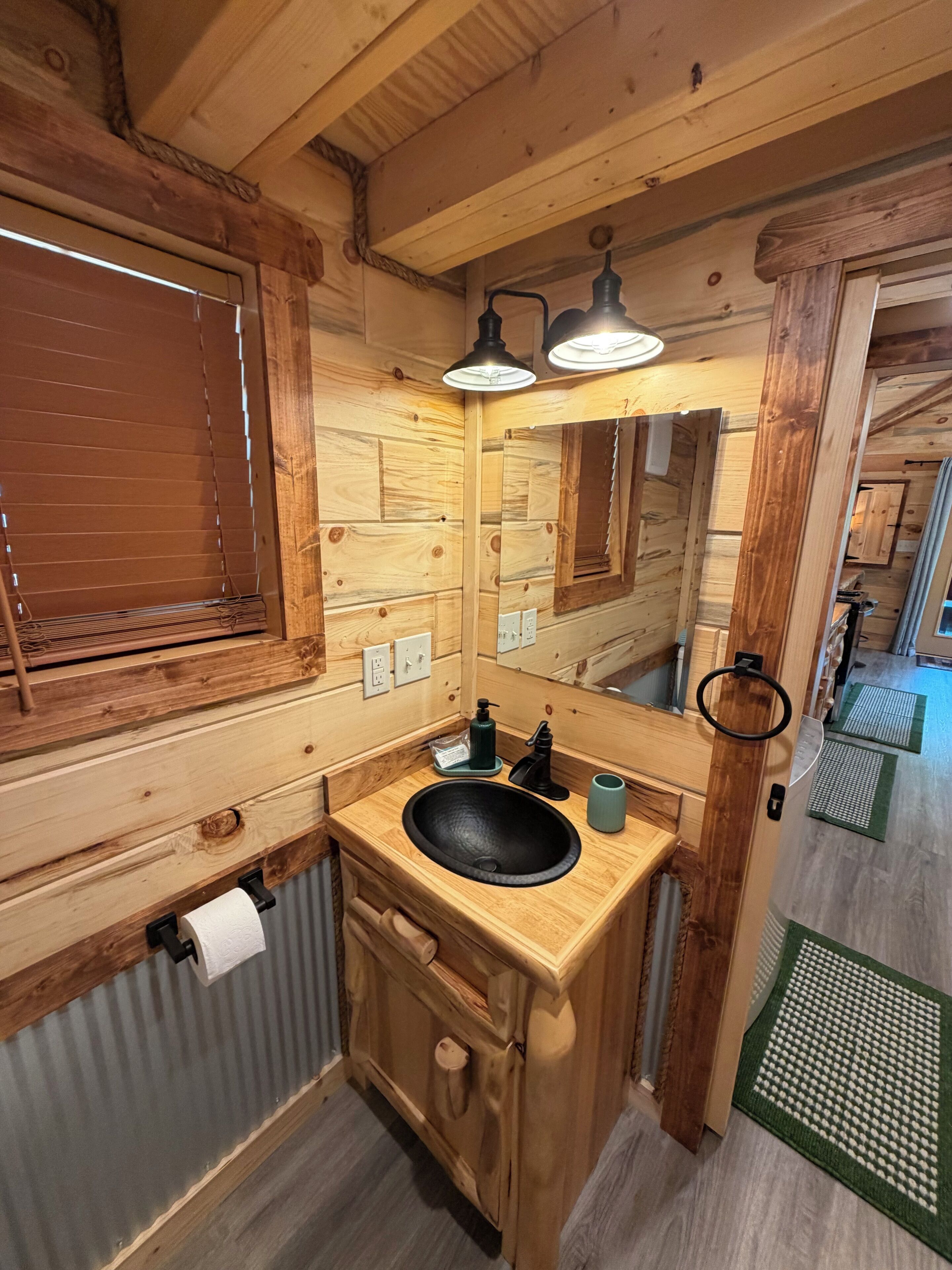 A wooden cabin-style bathroom with a wooden sink, a mirror, and a towel rack.