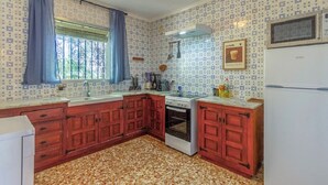 Una cocina con papel tapiz estampado, armarios de madera, una estufa y un refrigerador.