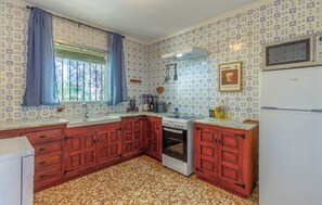Eine Küche mit strukturiertem Wandpapier, Holzschränken, einem Herd und einem Kühlschrank.