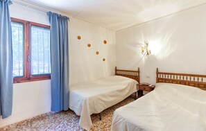 Ein Schlafzimmer mit zwei Betten, einem Fenster mit Vorhängen, einer Wanduhr und einem Nachttisch mit Lampe.