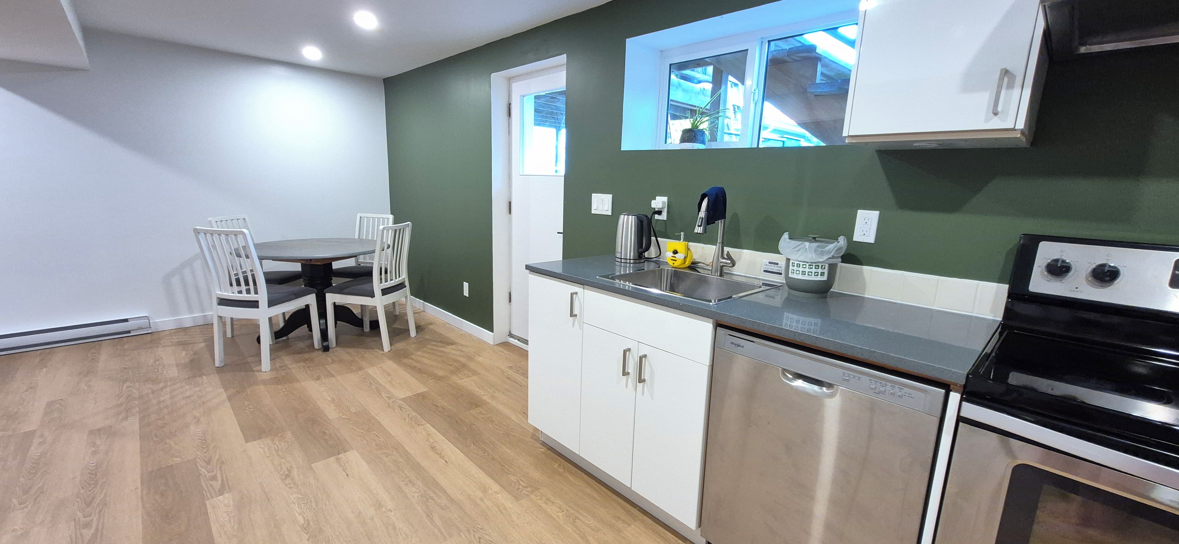 A compact kitchen with white cabinets, a stainless steel dishwasher, and a black stove.