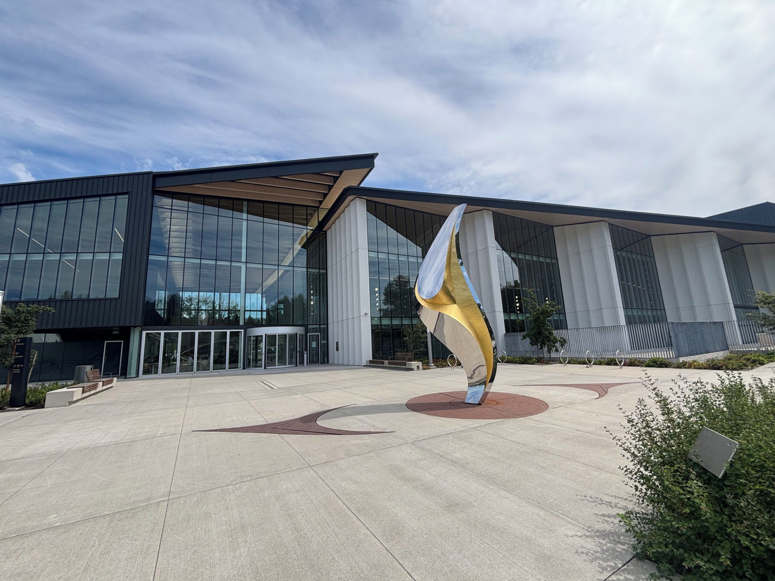 A modern building with large glass windows and a unique sculpture in the foreground.