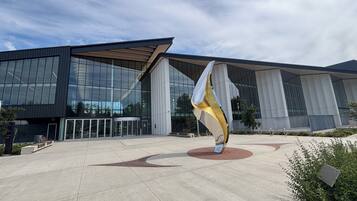 A modern building with large glass windows and a unique sculpture in the foreground.