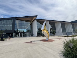 A modern building with large glass windows and a unique sculpture in the foreground.