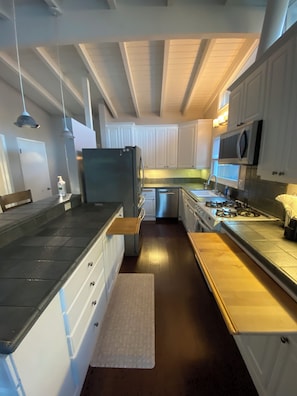 Eine moderne Küche mit weißen Schränken, einem Edelstahlkühlschrank, einem eingebauten Ofen und einer Mikrowelle.