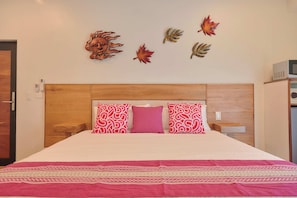 A bedroom with a wooden headboard, a bed with a white and red patterned bedspread, and decorative wall art. - Casa Macaria (Brisas de Zicatela)