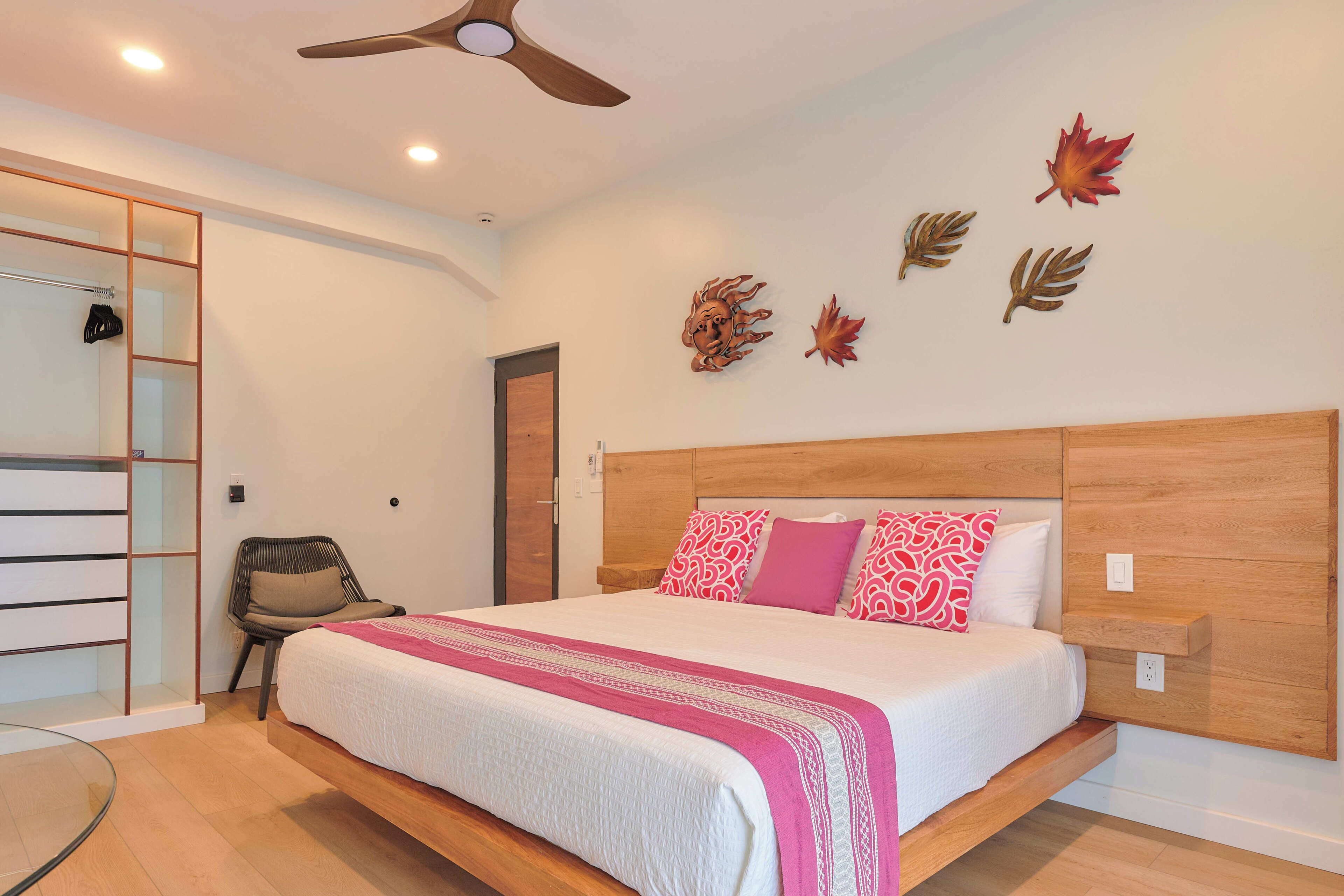 A bedroom with a bed, a chair, a wardrobe, and a ceiling fan.