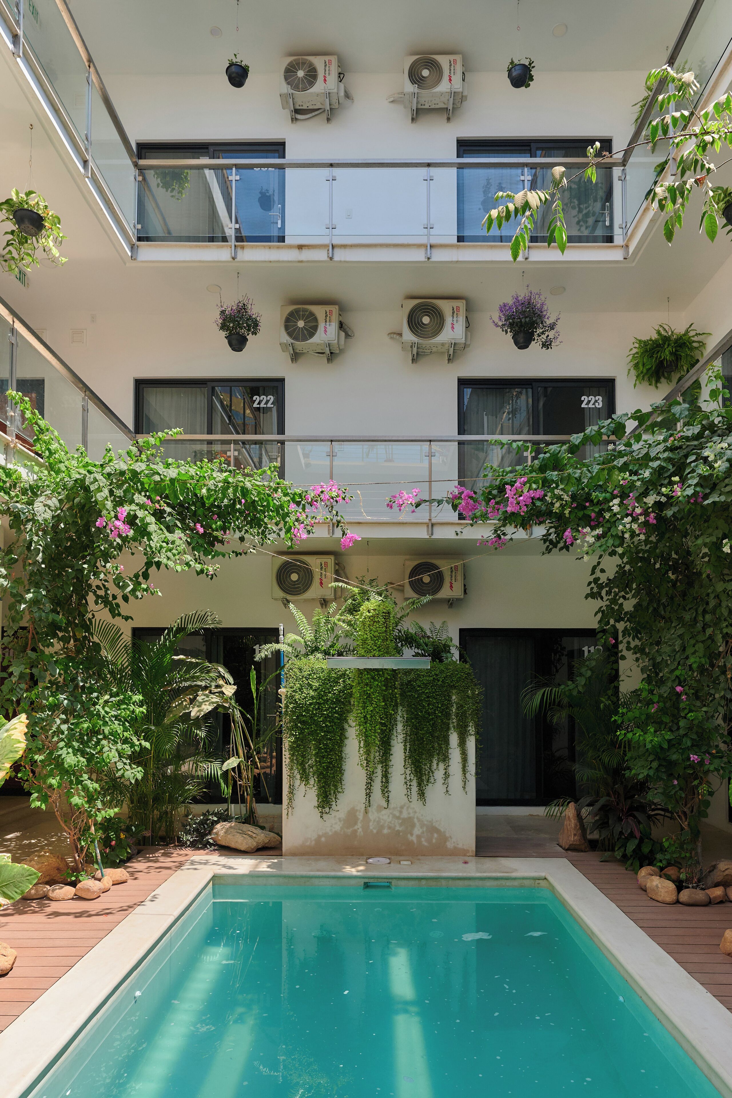 A multi-level building with a swimming pool, air conditioning units, and potted plants.