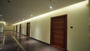 Un largo pasillo bien iluminado con varias puertas, piso pulido y luces empotradas en el techo.