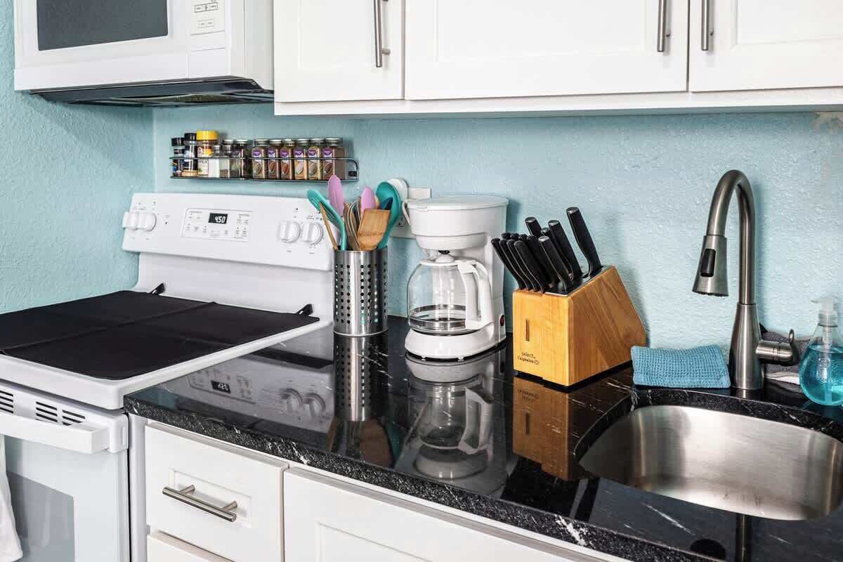 Une cuisine équipée d’un four à micro-ondes, d’une cuisinière, d’une machine à café et d’un bloc à couteaux.
