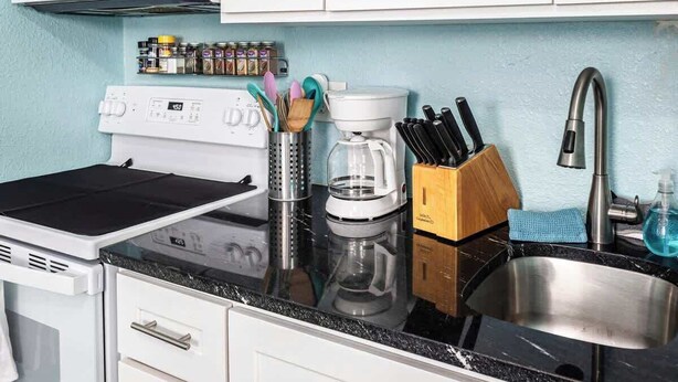 A kitchen with a microwave, stove, coffee maker, and a knife block. - Quiet Palm Loft Near Lake w/ BBQ & Patio (Lakeland)