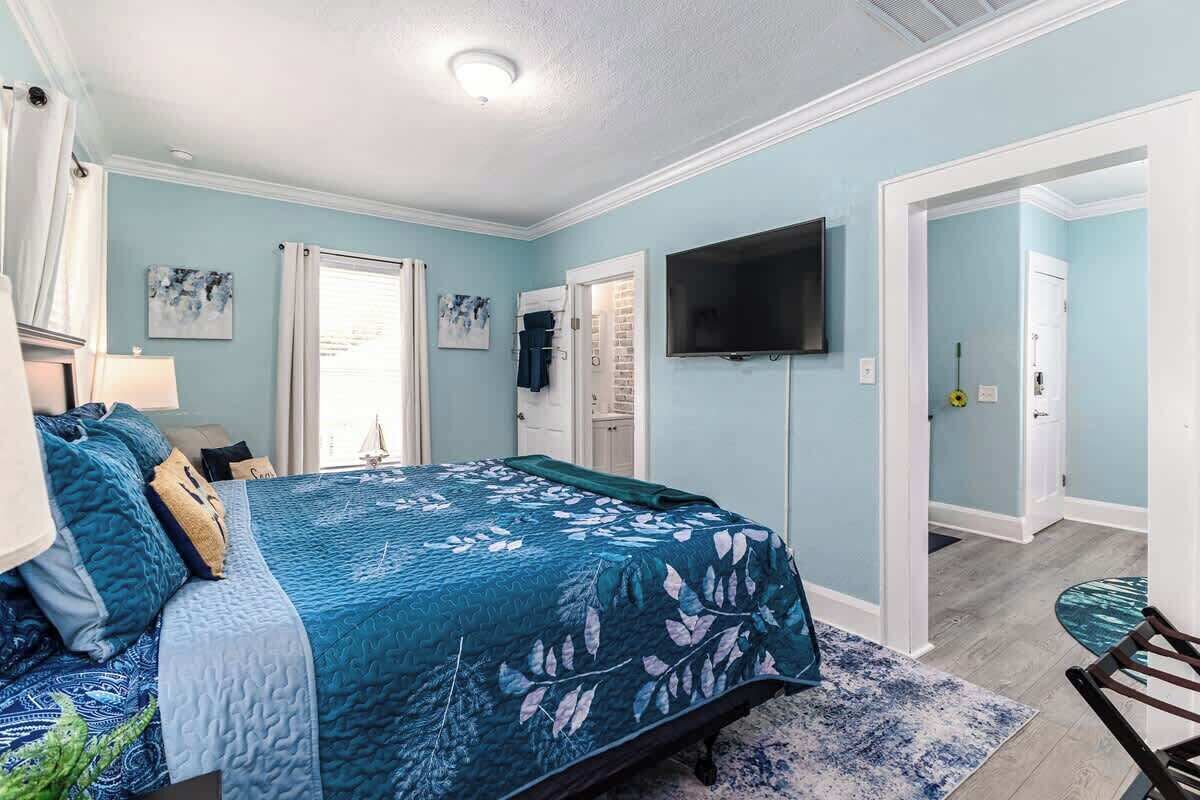 Ein Schlafzimmer mit einem Bett, einem Fernseher, einer Tür und einem Fenster.