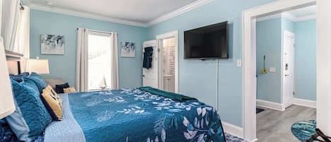 Ein Schlafzimmer mit einem Bett, einem Fernseher, einer Tür und einem Fenster.