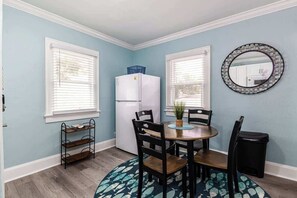 A dining area with a round table, chairs, a small potted plant, and a trash bin. - Quiet Palm Loft Near Lake w/ BBQ & Patio (Lakeland)