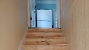 A wooden staircase leading to a room with a white door and a window with blinds. - Quiet Palm Loft Near Lake w/ BBQ & Patio (Lakeland)