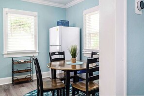 A dining area with a round table, six chairs, a white refrigerator, and a small plant on the table. - Quiet Palm Loft Near Lake w/ BBQ & Patio (Lakeland)