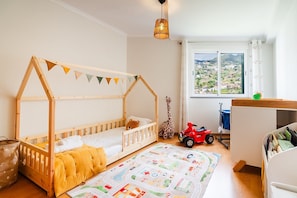 Ein Kinderzimmer mit einem hölzernen Etagenbett, einer Spielmatte, einem Giraffenspielzeug und einem roten Spielzeugauto.