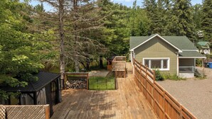 A wooden deck with a fenced area, a small cabin, and a house with a green roof. - A beautiful cabin with a private lake. (Saint-Cã´Me)
