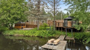 A lakeside property with a wooden dock, a cabin, and a house with a deck. - A beautiful cabin with a private lake. (Saint-Cã´Me)