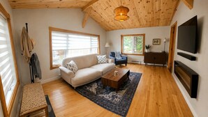 A living room with a sofa, coffee table, and a TV. - A beautiful cabin with a private lake. (Saint-Cã´Me)