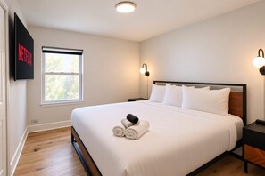 A hotel room with a bed, a TV mounted on the wall, a window, and a bedside lamp. - 2Bd 1Bth Apt. | 100"TV | 3GB WIFI (Denver)
