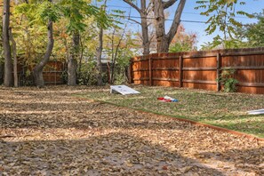 A backyard with a wooden fence, leaf-covered ground, and a white object on the grass. - 2Bd 1Bth Apt. | 100"TV | 3GB WIFI (Denver)