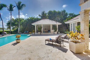 Un espace piscine aménagé avec des chaises longues, un gazebo et des plantes en pot.