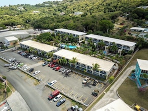Ein mehrstöckiges Hotel mit Parkplatz, umgeben von Grünflächen und Hügeln.