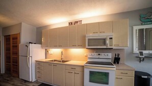 A compact kitchen with a refrigerator, microwave, stove, and sink. - Caribbean Blue Hideaway | 1BR Condo w/ Ocean View (Christiansted)