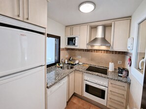 Eine kompakte Küche mit integriertem Mikrowellenherd, Spülbecken aus Edelstahl und einem Backofen mit zwei Garstufen.