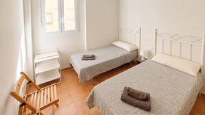 A bedroom with two single beds, a desk, a chair, and a window. - Las Arenas T2 - Apartment with sea view (Isla Canela)