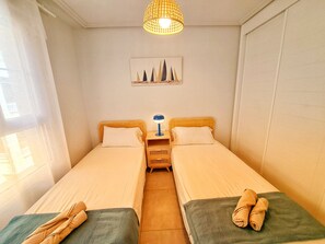 Ein Doppelzimmer mit zwei Betten, einem Nachttisch, einer Lampe und einem Bild an der Wand.