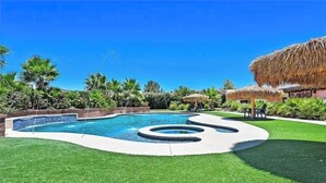 A swimming pool with a unique design, surrounded by well-maintained grass and palm trees. - Tropical Private Estate • 8 Bdrm • Resort Pool • 5 Mins to the Strip  • Weddings (Las Vegas)