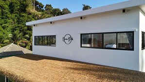 A modern villa with a white exterior, two windows, and a logo on the wall. - Ocean Peek Villa-Bang Po  (Chang Wat Surat Thani)