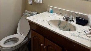 Baño con inodoro, lavamanos, espejo y toallero.