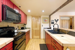 A kitchen with a microwave, stove, sink, and wooden cabinets. - New Listing! Pet Friendly Townhome - Fenchurch Trails (Park City)