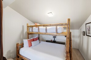 Ein Etagenbett mit Holzrahmen und weißer Bettwäsche.