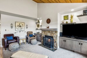 Ein modernes Wohnzimmer mit Kamin, Ledersofas, einem Flachbildfernseher und Wandbildern.