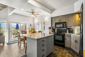 A modern kitchen with a central island, stainless steel appliances, and a dining area with a view. - Bird House on the beautiful Deschutes River. Dog Friendly (Redmond)