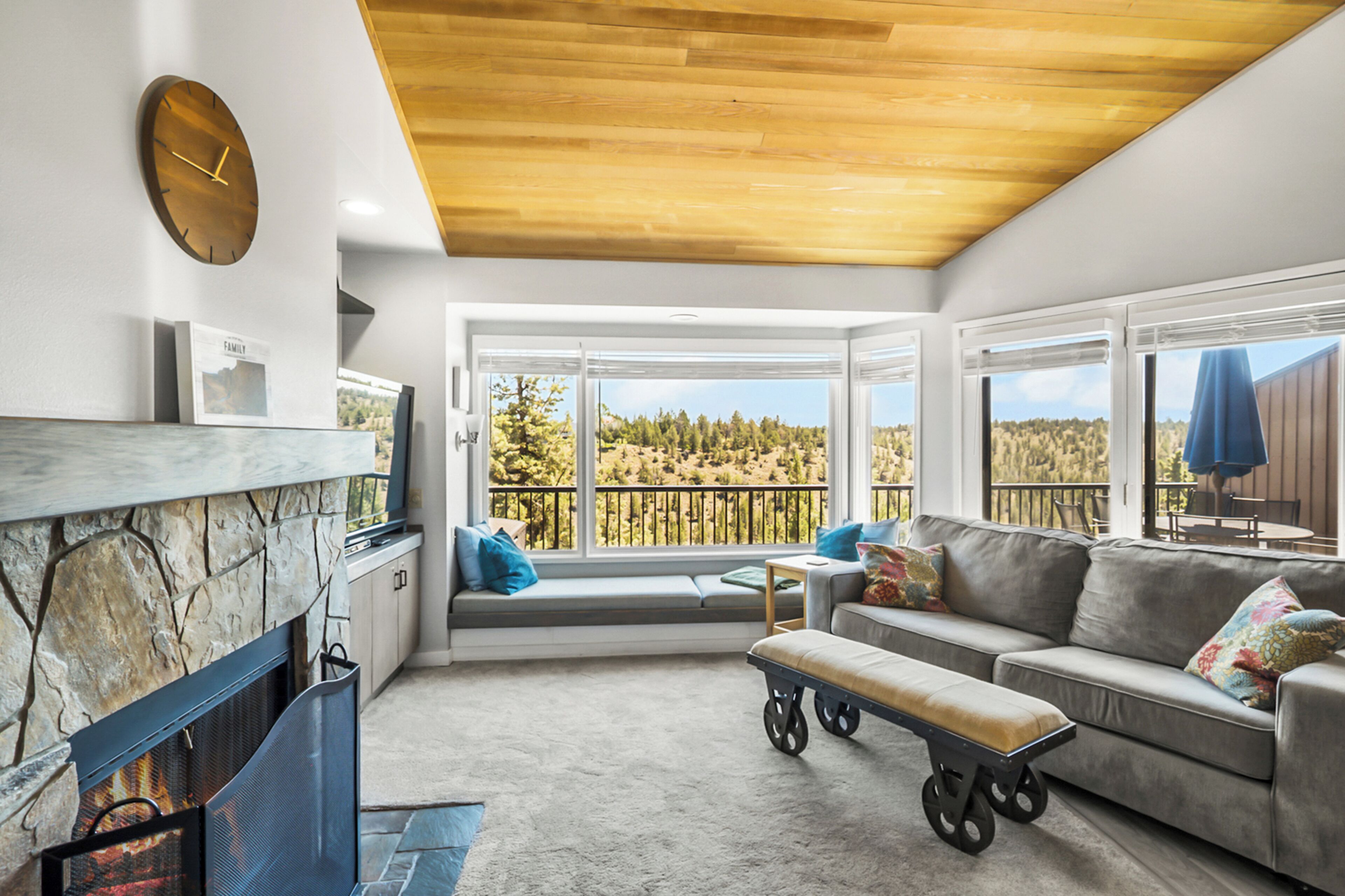 A modern living room with a fireplace, seating area, and large windows offering a view of the outdoors.