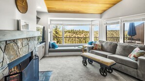 Uma sala de estar moderna com lareira, área de estar e grandes janelas com vista para o exterior.