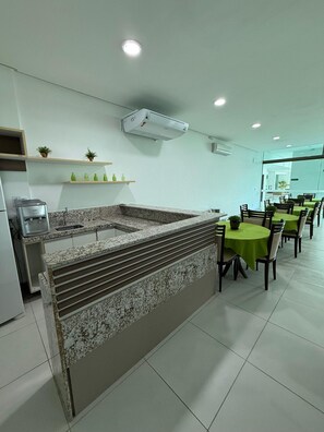 Eine moderne Küche mit Granit-Arbeitsplatten, einer eingebauten Spüle und einem Essbereich mit runden Tischen und Stühlen.