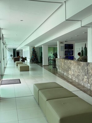 Eine moderne Hotelhalle mit Empfangsschalter, Sitzgelegenheiten und einem Weihnachtsbaum.