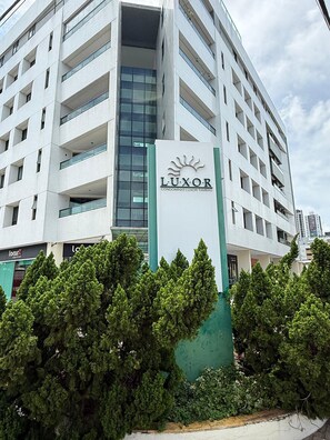 A multi-story building with a sign reading 'LUXOR CONDOMINIO LUXOR TAMBAU'.