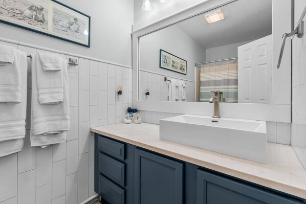 A bathroom with a white sink, dark cabinets, and a large mirror. - Drift Away Pet Friendly Beach Side Town Home (Surfside)