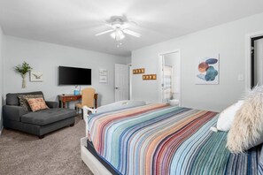A bedroom with a bed, a sofa, a desk, a television, and a ceiling fan. - Drift Away Pet Friendly Beach Side Town Home (Surfside)