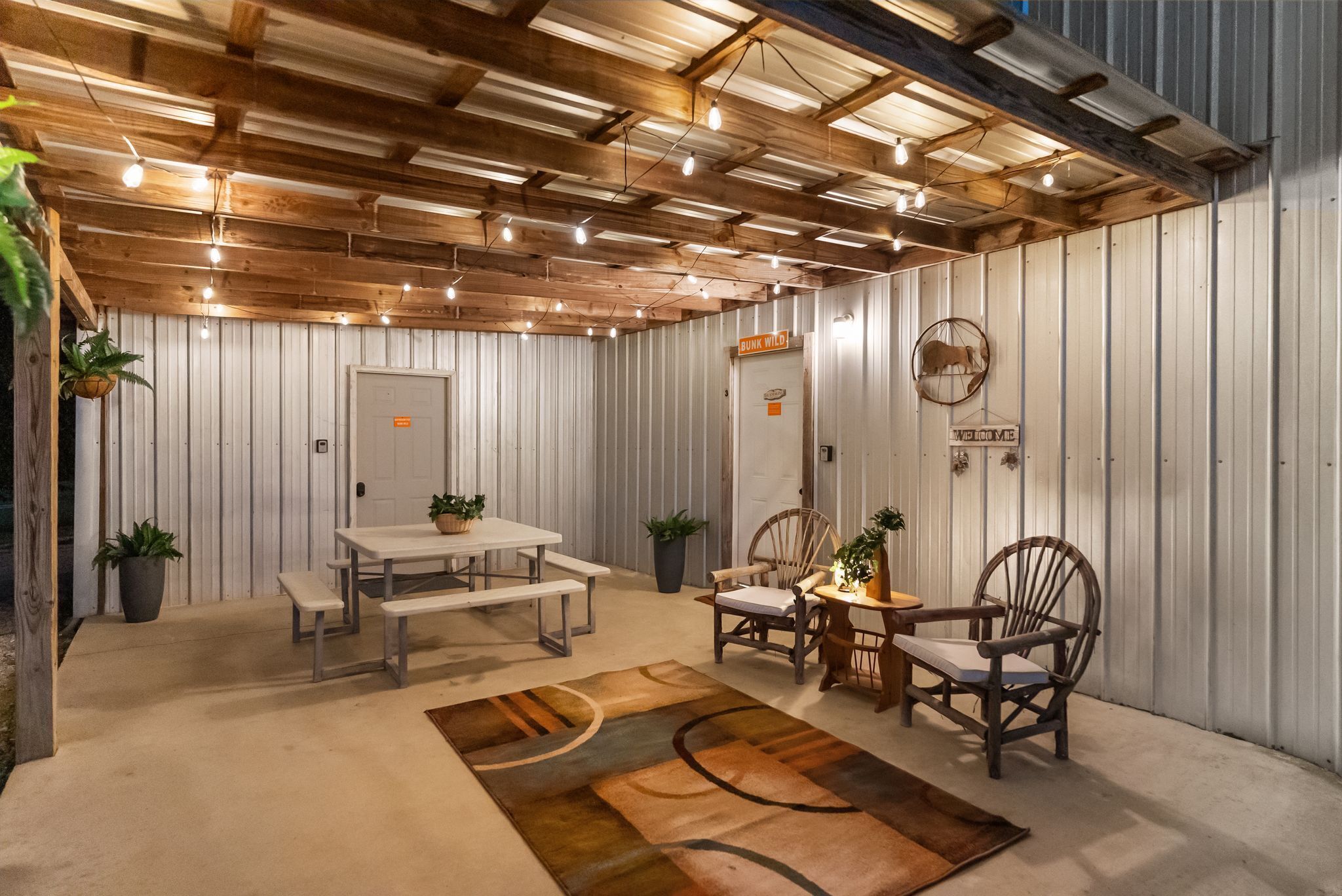 A rustic interior with a wooden ceiling, metal walls, a white door, and a table with benches.